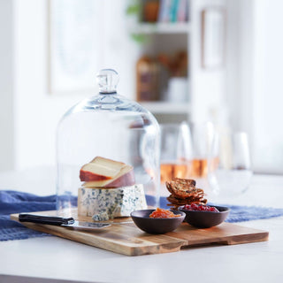 Libbey Acaciawood cheese board set with glass dome, ceramic bowls, and knife, elegantly displaying cheese and crackers.